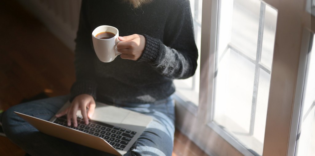 Person on computer holding a cup a coffee 